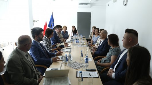 Zdjęcie przedstawia osoby uczestniczące w spotkaniu prezesa UODO z inspektorami ochrony danych w sądach. Uczestnicy spotkania siedzą po obu stronach stołu, po prawej stronie znajduje się prezes UODO Mirosław Wróblewski 